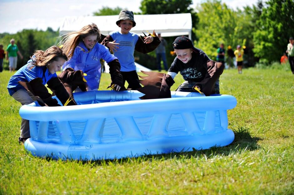Children play in an inflatable pool while wearing crafted bird wings.