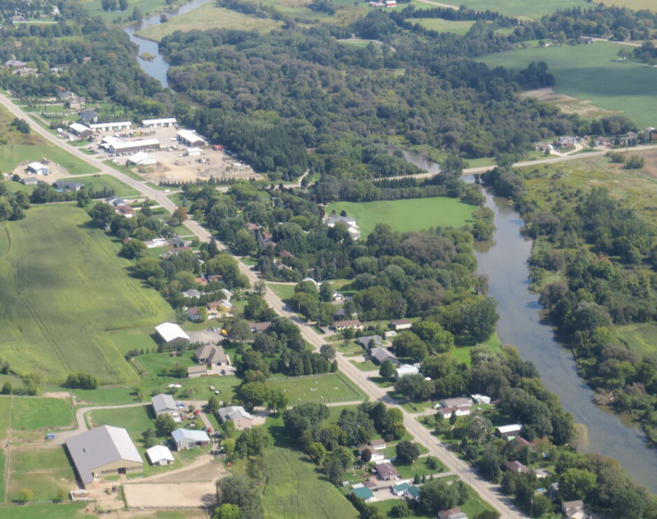 An aerial view of a river running through a residential area and agricultural area.