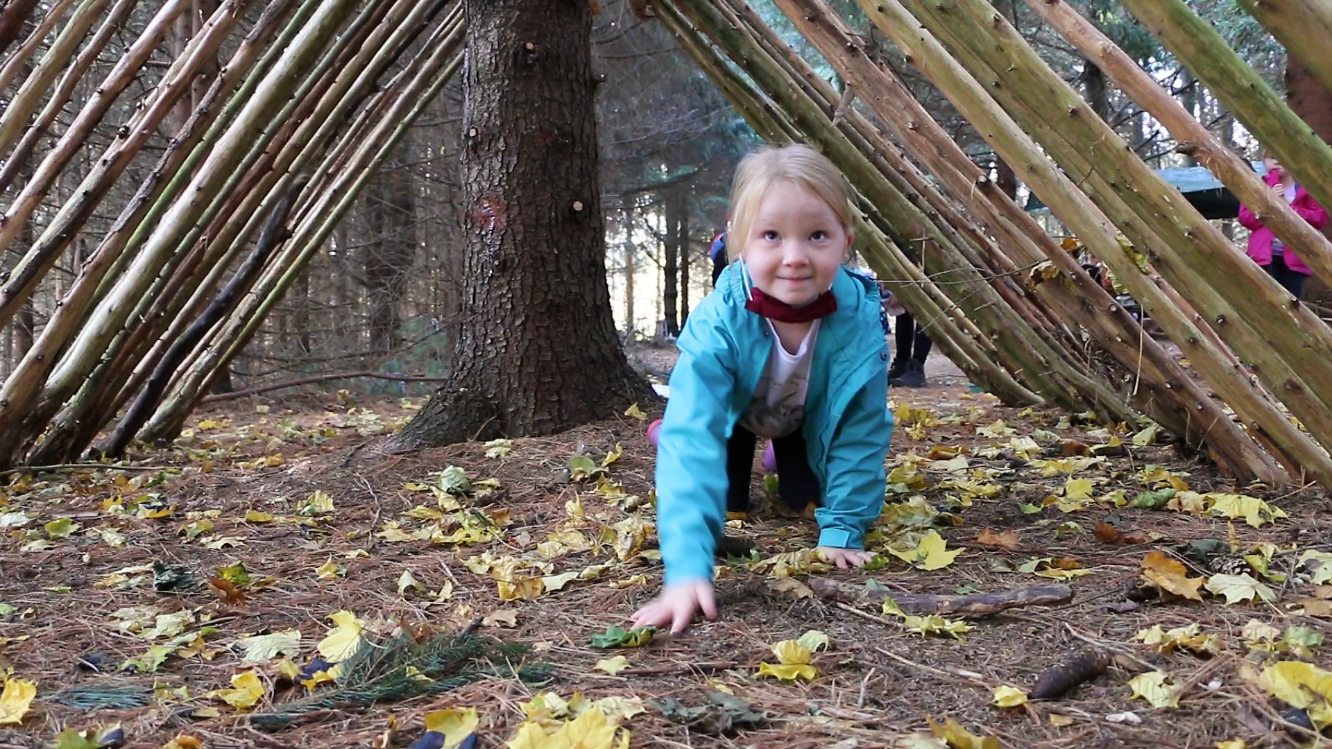 Child crawling through a tunnel made of branches in the woods