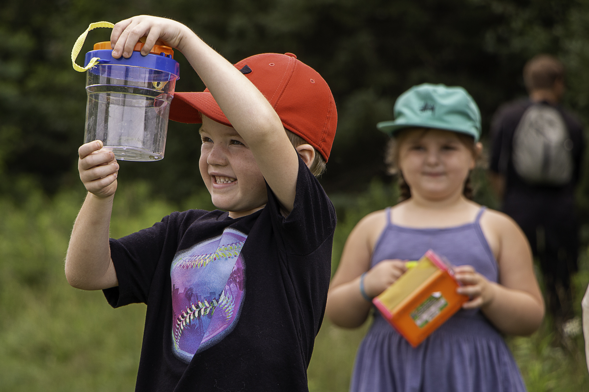 Child smiles while holding insect container
