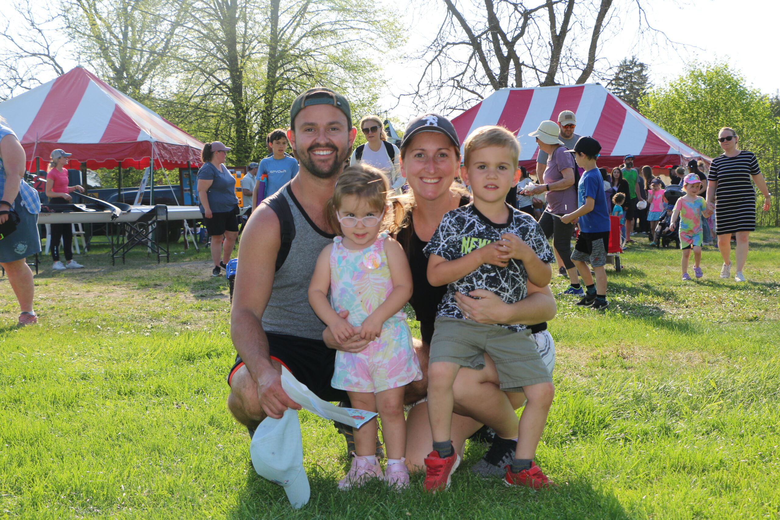 52892032020_3cd340907a_5k Two adults and two children pose for a photo near festival tents.