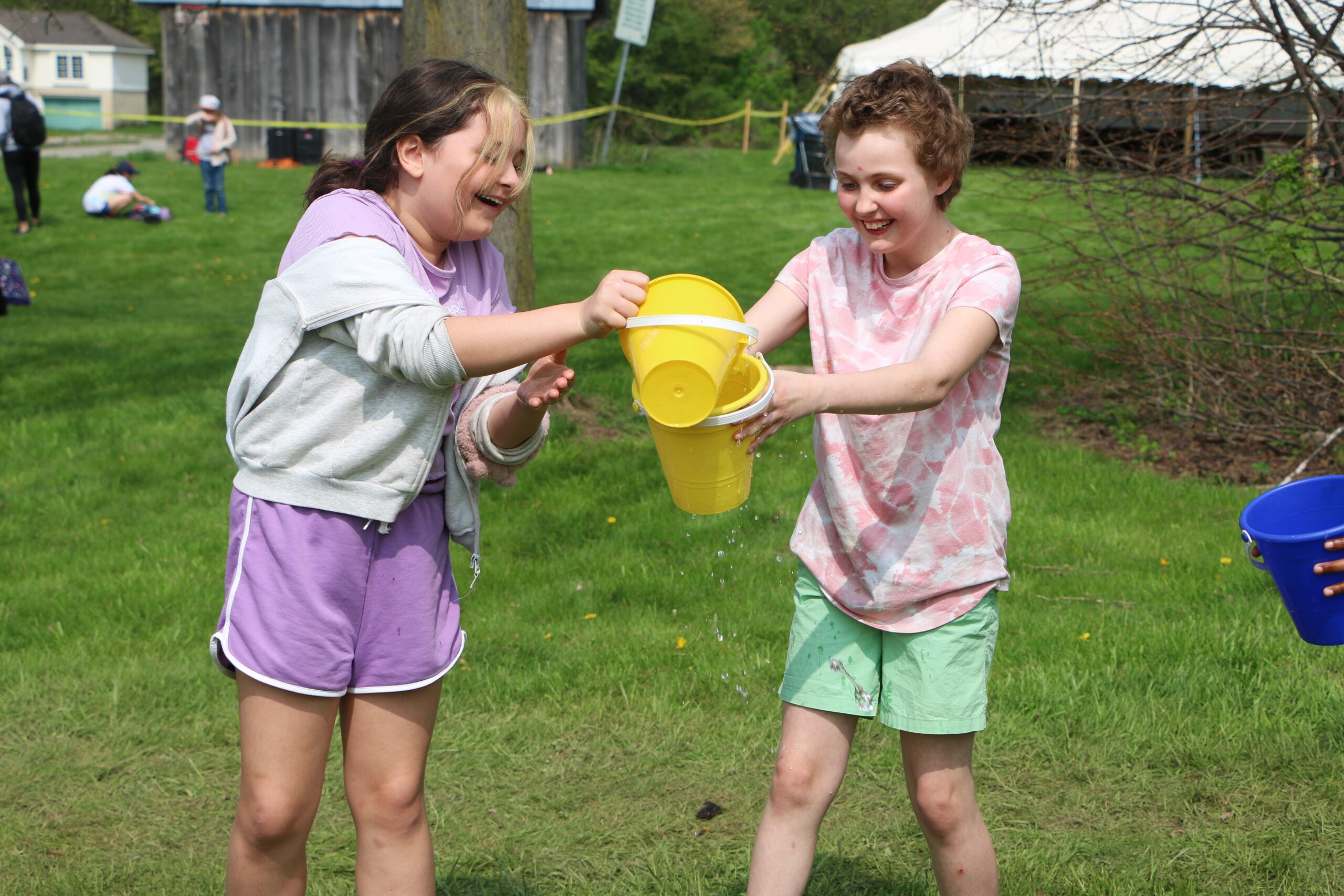 Two children play with plastic buckets of water.