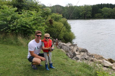 A dad and young son hold a fishing rod