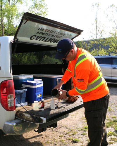 A male staff pours collected water into a vessel for testing