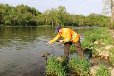 A male staff collects water from the river