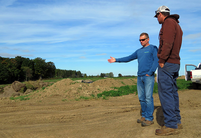 UTRCA staff stands next to landowner in a farm field