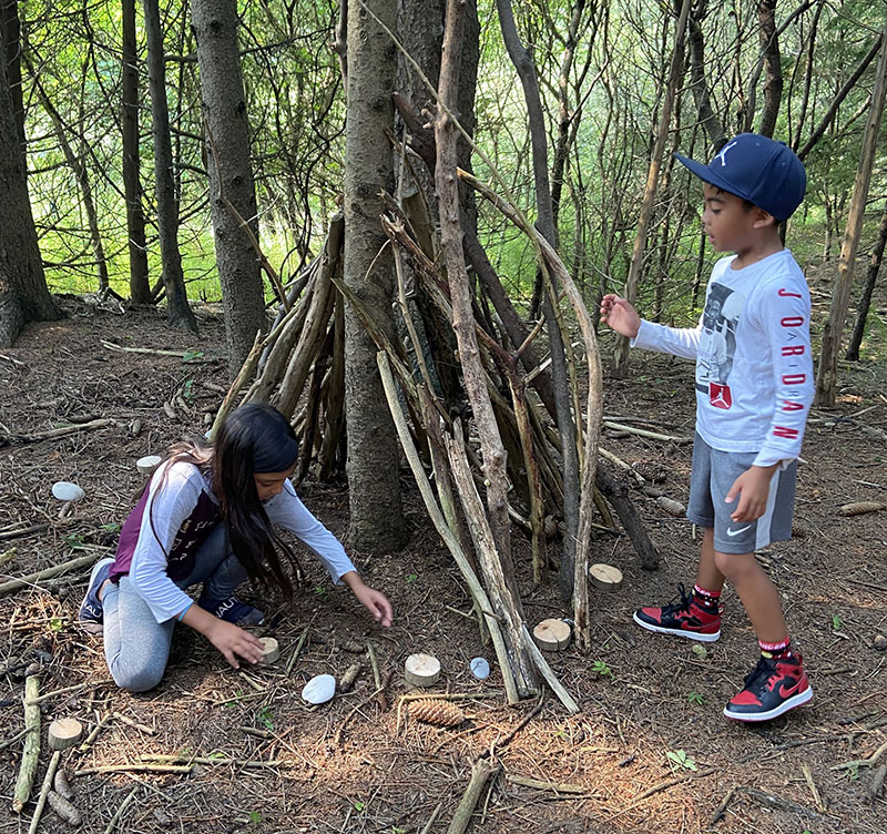 Two children playing in the woods at Nature School