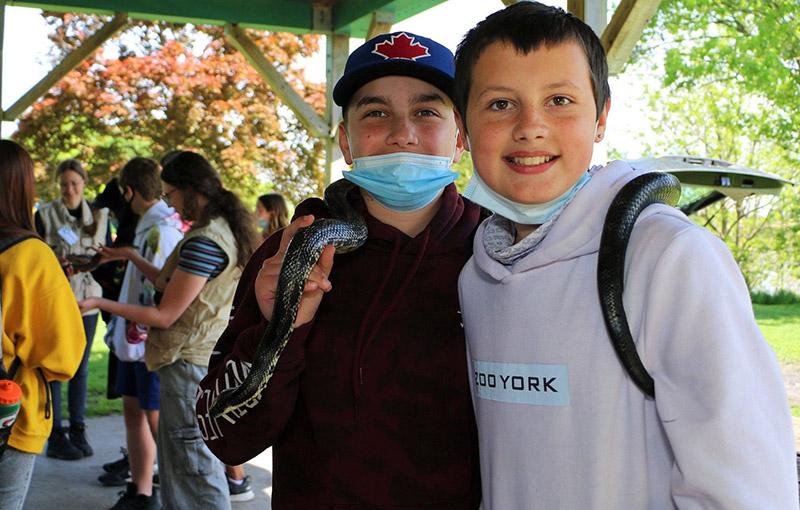 Students hold a large snake while other students talk in the background