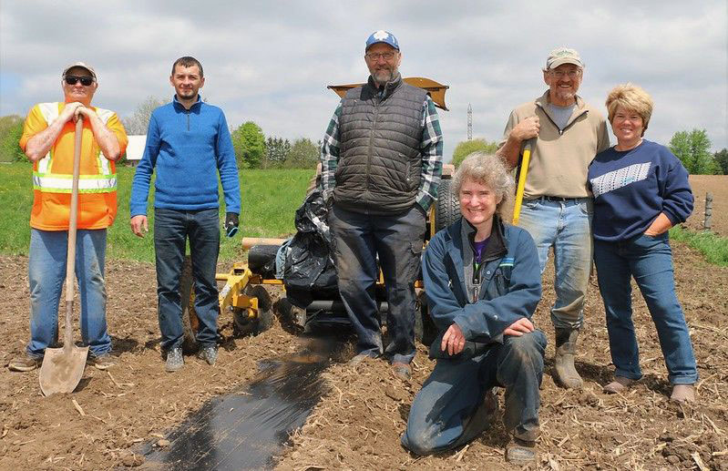 Group of people with shovels in a plowed farm field
