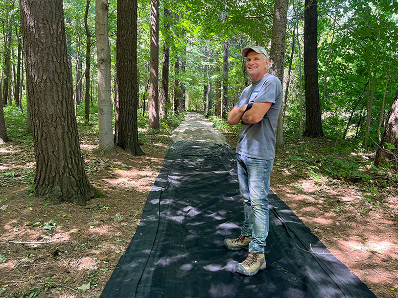 Person stands on black filtercloth on a trail in the woods