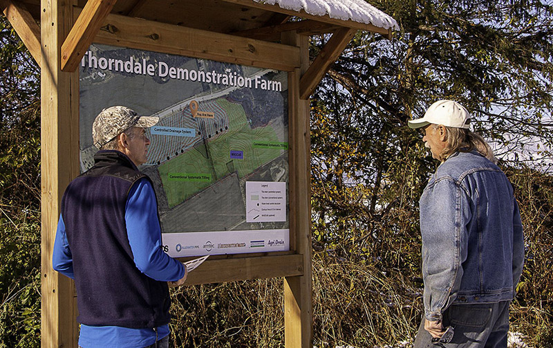 UTRCA staff talk with landowner next to a kiosk with a sign at the Demonstration Farm Conservation Field Day