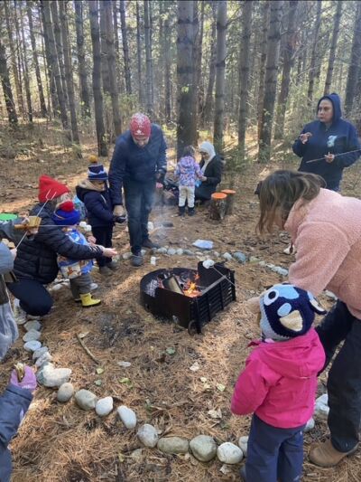 Caregivers and children gathered around a small fire pit, toasting marshmallows
