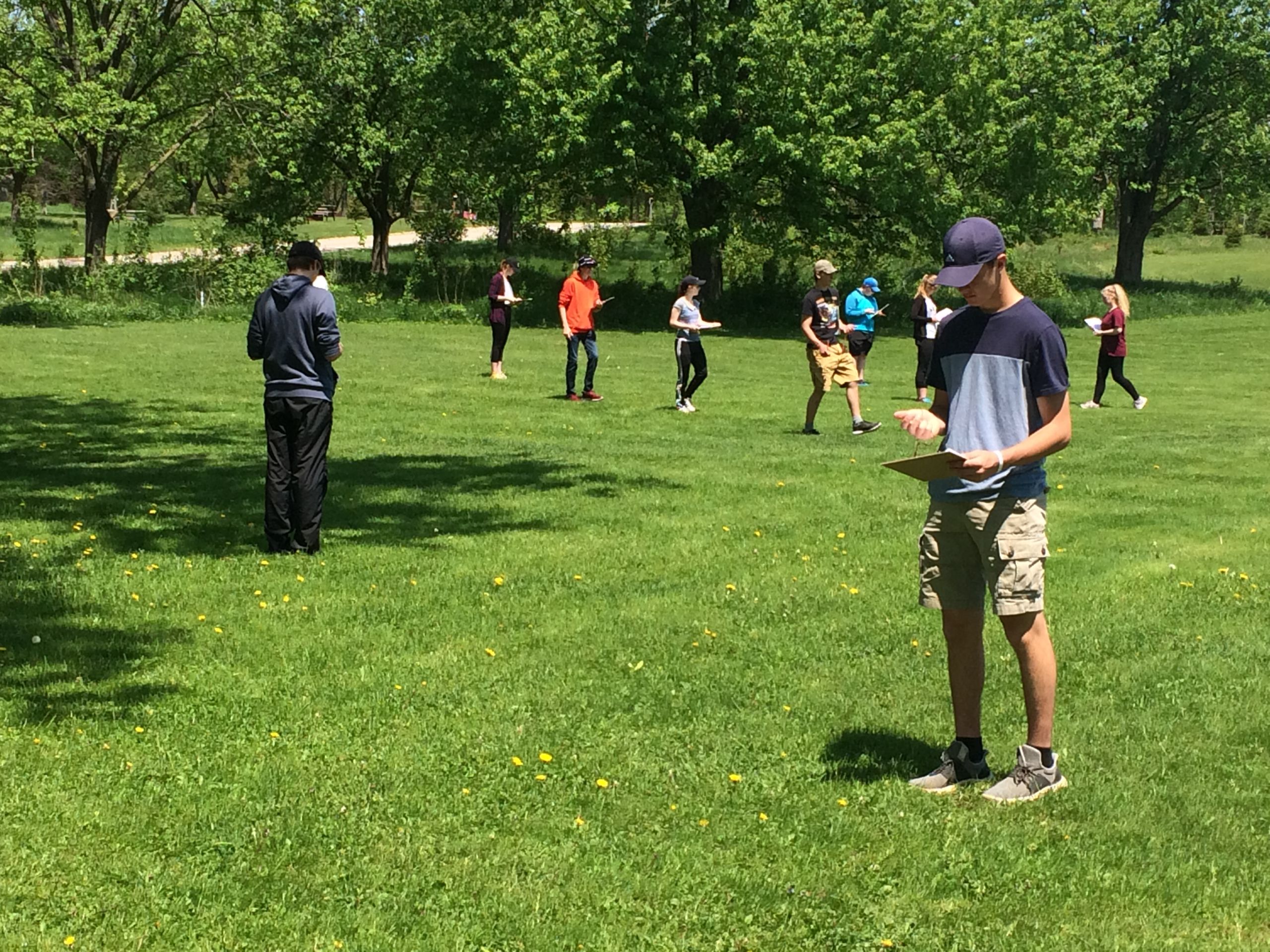 Finding Your Way GDCI and DVCI Students standing and walking in a grassy field, looking at compasses and clipboards they are holding