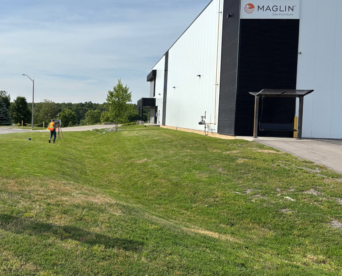 Person wearing safety vest walks across a grassy area next to a large building