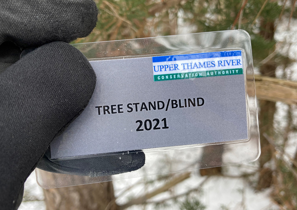 Person's hand holding a UTRCA tree stand tag for 2021