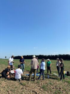 Attendees standing in field listening to staff presentation