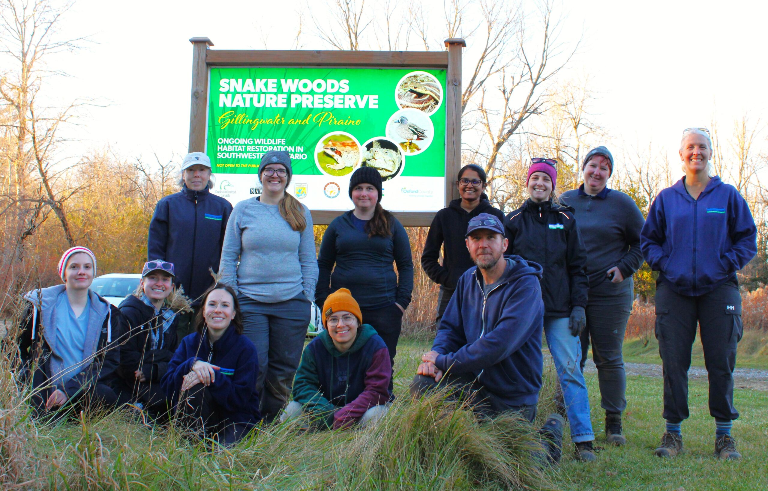 UTRCA staff pose in front of a sign for Snake Woods Nature Preserve.