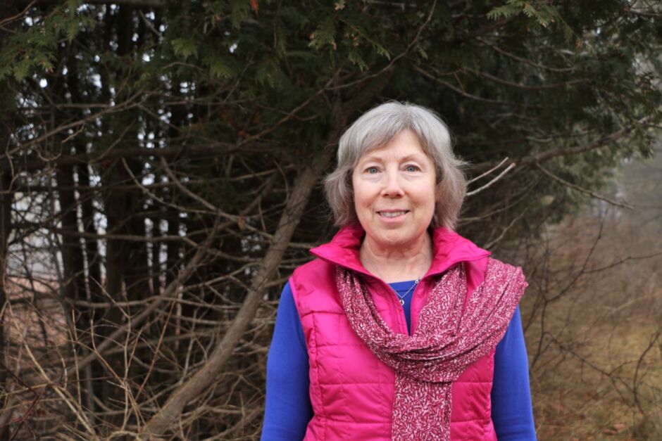 A photo of Cathy Quinlan standing outside in front of trees