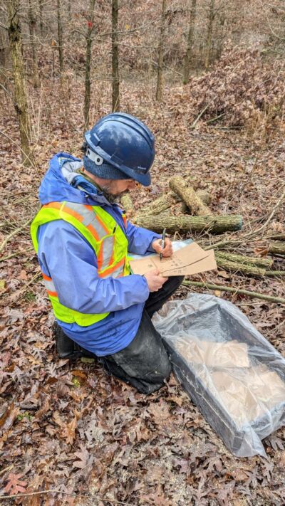 A staff person makes notes on tree labels