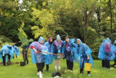 Group of five students in rain ponchos with planting equipment