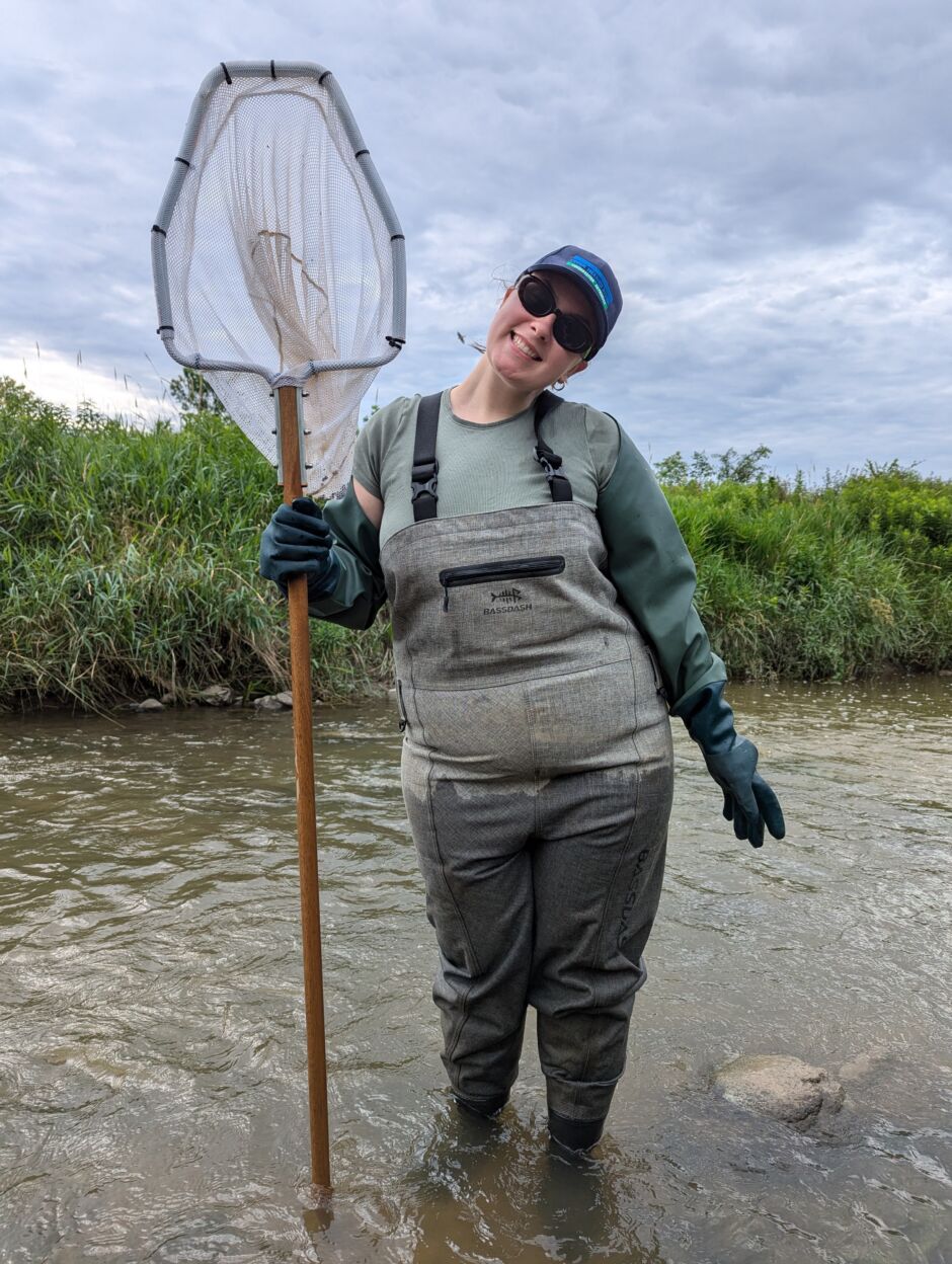 A person stand in a creek holding a large net