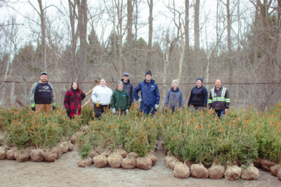 A crew of staff stand behind burlap trees