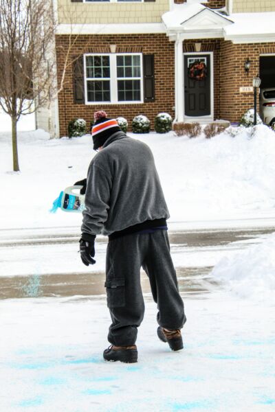 A man spreading salt on his driveway
