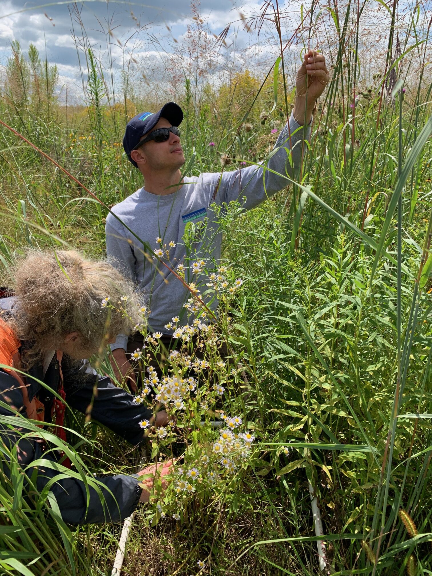 Two people looking at vegetation in a prairie